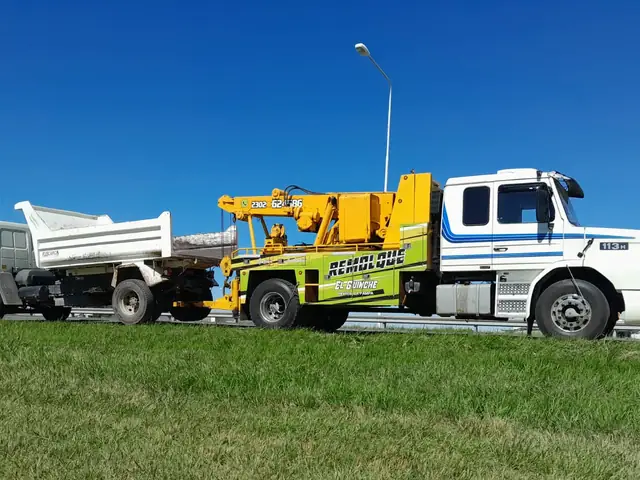 Grúa pesada trabajando junto a camión hormigonero